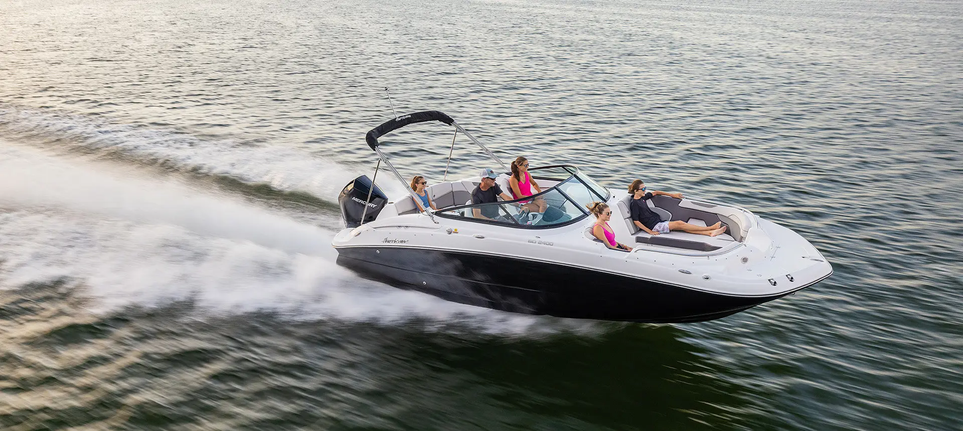 side view of a hurricane sundeck 2400 ob deck boat speeding across a lake