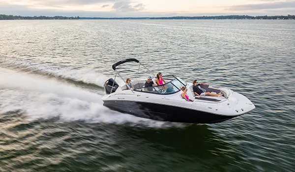 side view of a hurricane sundeck 2400 ob deck boat speeding across a lake