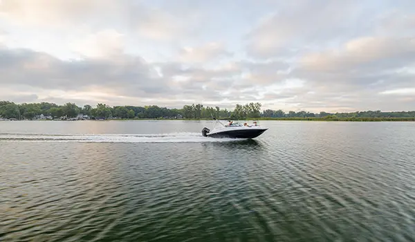 long distance side view of a hurricane sundeck 2400 ob deck boat on a lake