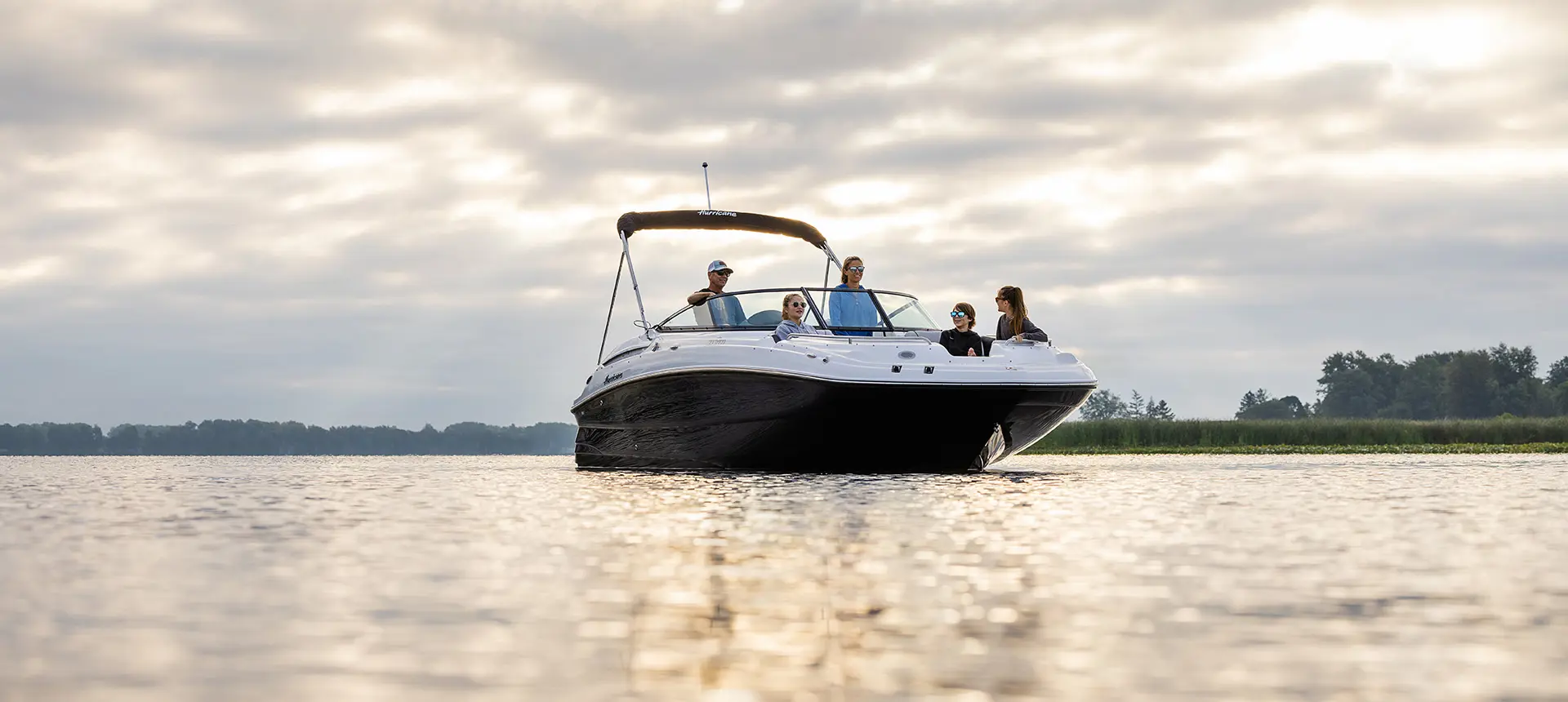 bow focused view of a family relaxing on a hurricane sundeck 2400 ob deck boat