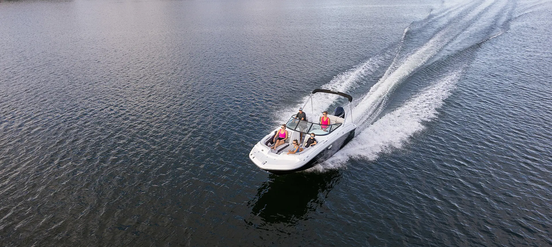 aerial view of a hurricane sundeck 2400 ob deck boat speeding across a lake