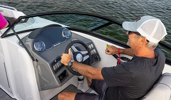 man sitting at the helm of a hurricane sundeck 2400 ob deck boat