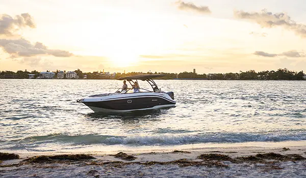 Hurricane Sundeck 2600 OB deck boat pulling up to the shore.