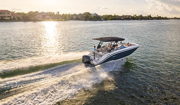 Rear-aerial view of a Hurricane Sundeck 2600 OB deck boat cruising in a bay.