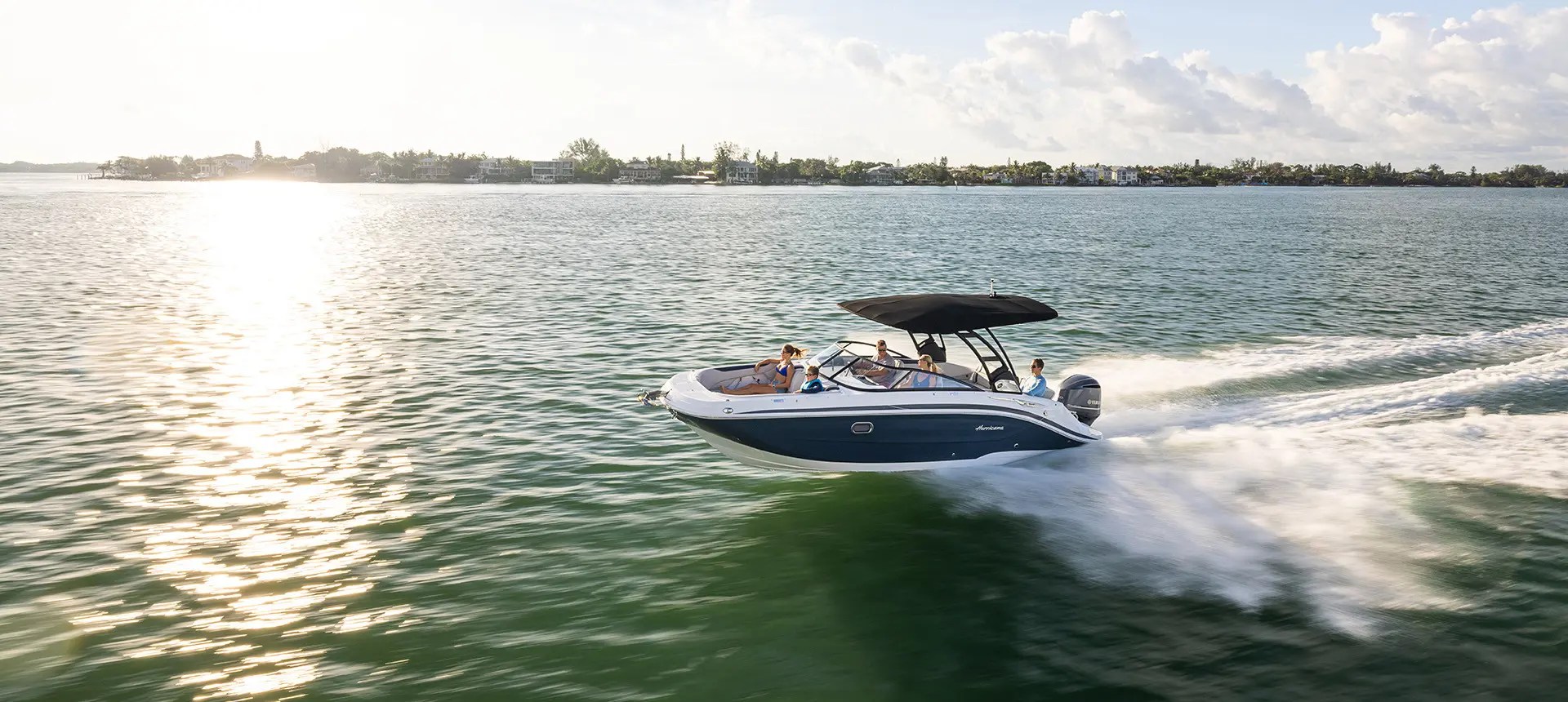 Side-view of a Hurricane Sundeck 2600 OB deck boat speeding across the ocean.