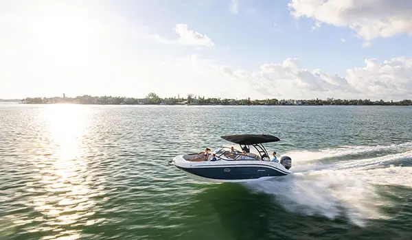 Side-view of a Hurricane Sundeck 2600 OB deck boat speeding across the ocean.