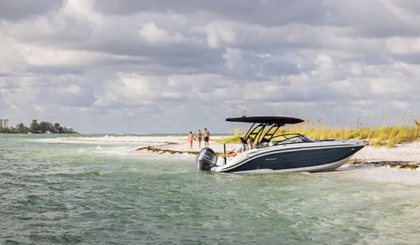 A couple relaxing on the stern seats on a beached Hurricane Sundeck 2600 OB deck boat.