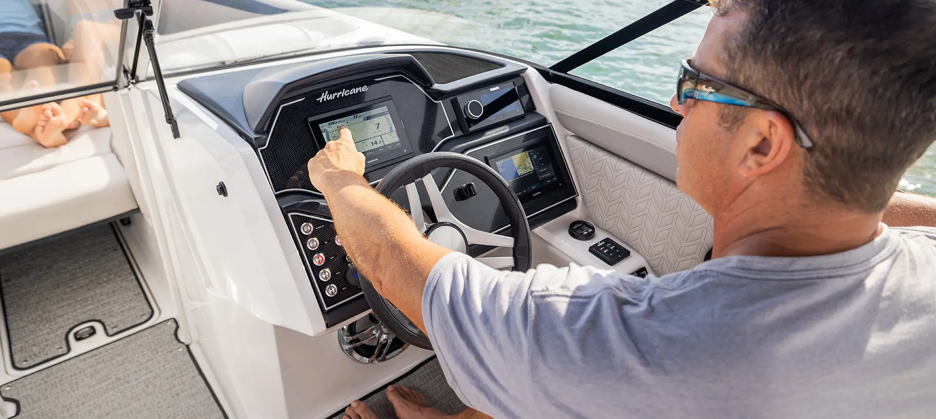 Man pointing to the Garmin GPS on the helm of a Hurricane Sundeck 2600 OB deck boat.