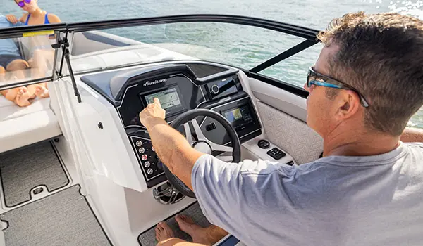 Man pointing to the Garmin GPS on the helm of a Hurricane Sundeck 2600 OB deck boat.