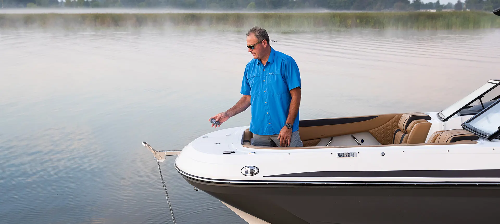 man lowering the remote controlled anchor on the bow of a hurricane sundeck 2600 ob deck boat
