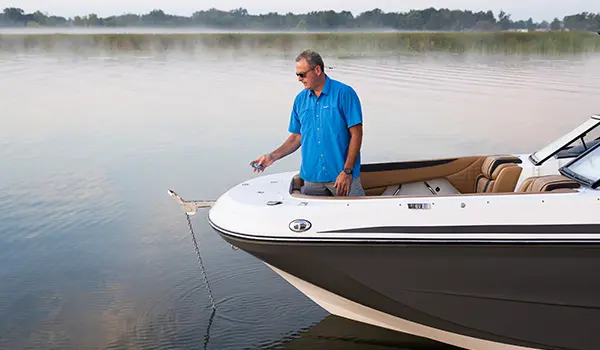 man lowering the remote controlled anchor on the bow of a hurricane sundeck 2600 ob deck boat