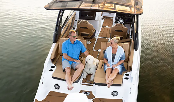 a couple relaxing with their dog on the stern swingback seats on a hurricane sundeck 2600 ob deck boat