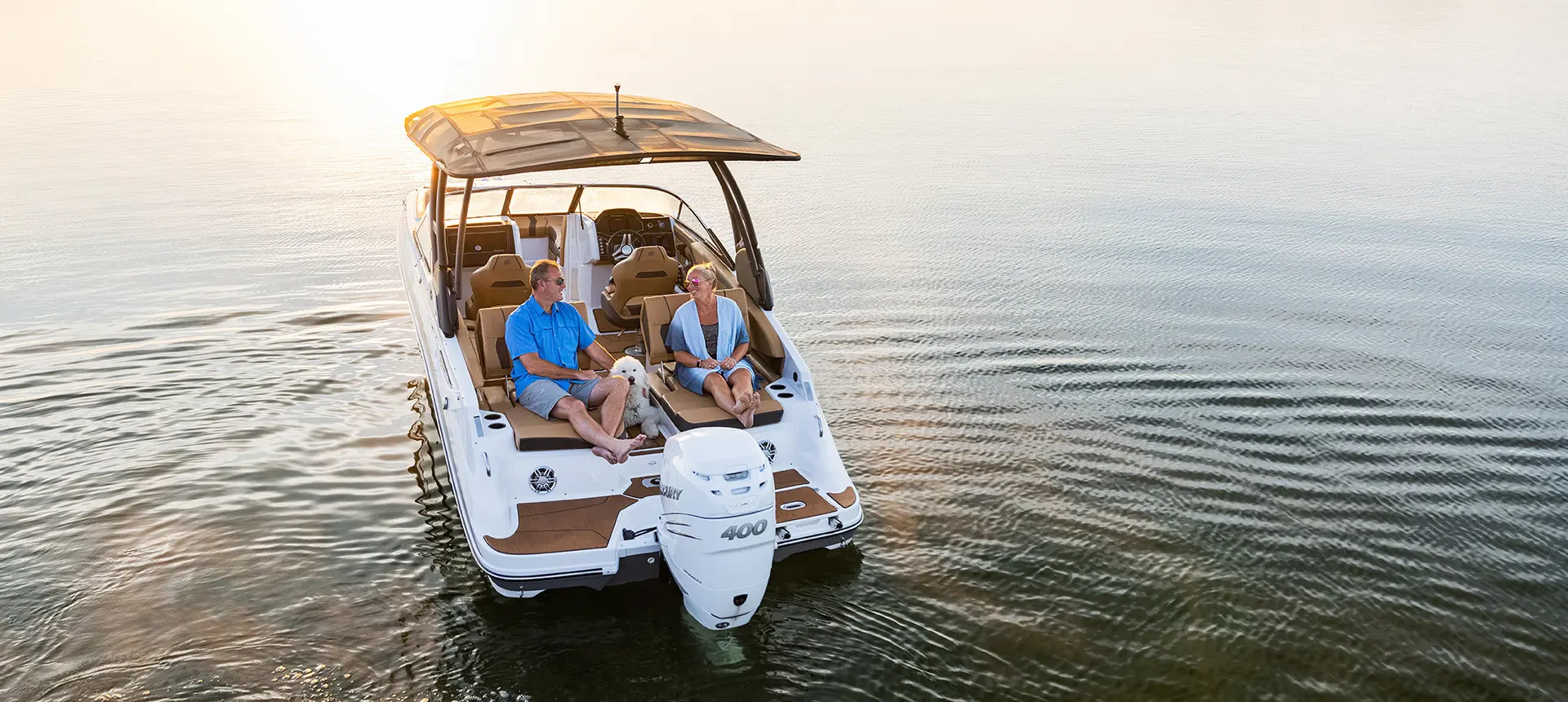a couple with their dog on the stern of a hurricane sundeck 2600 ob deck boat