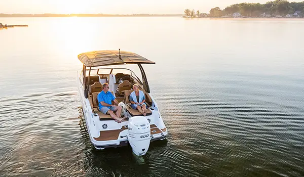 a couple with their dog on the stern of a hurricane sundeck 2600 ob deck boat
