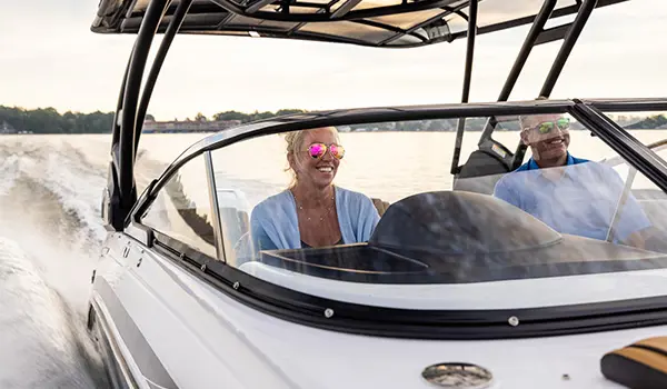 woman smiling at the helm of a hurricane sundeck 2600 ob deck boat