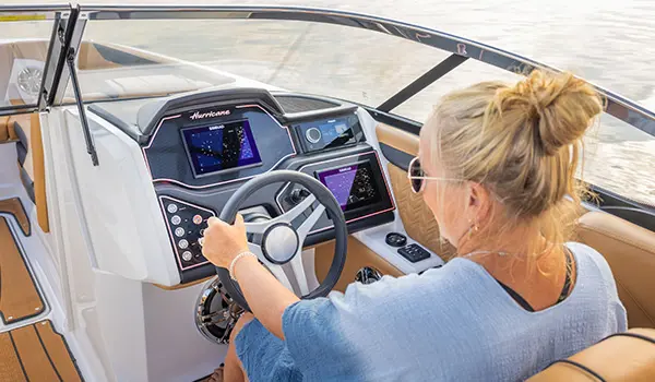 woman grasping the wheel at the helm of a hurricane sundeck 2600 ob deck boat