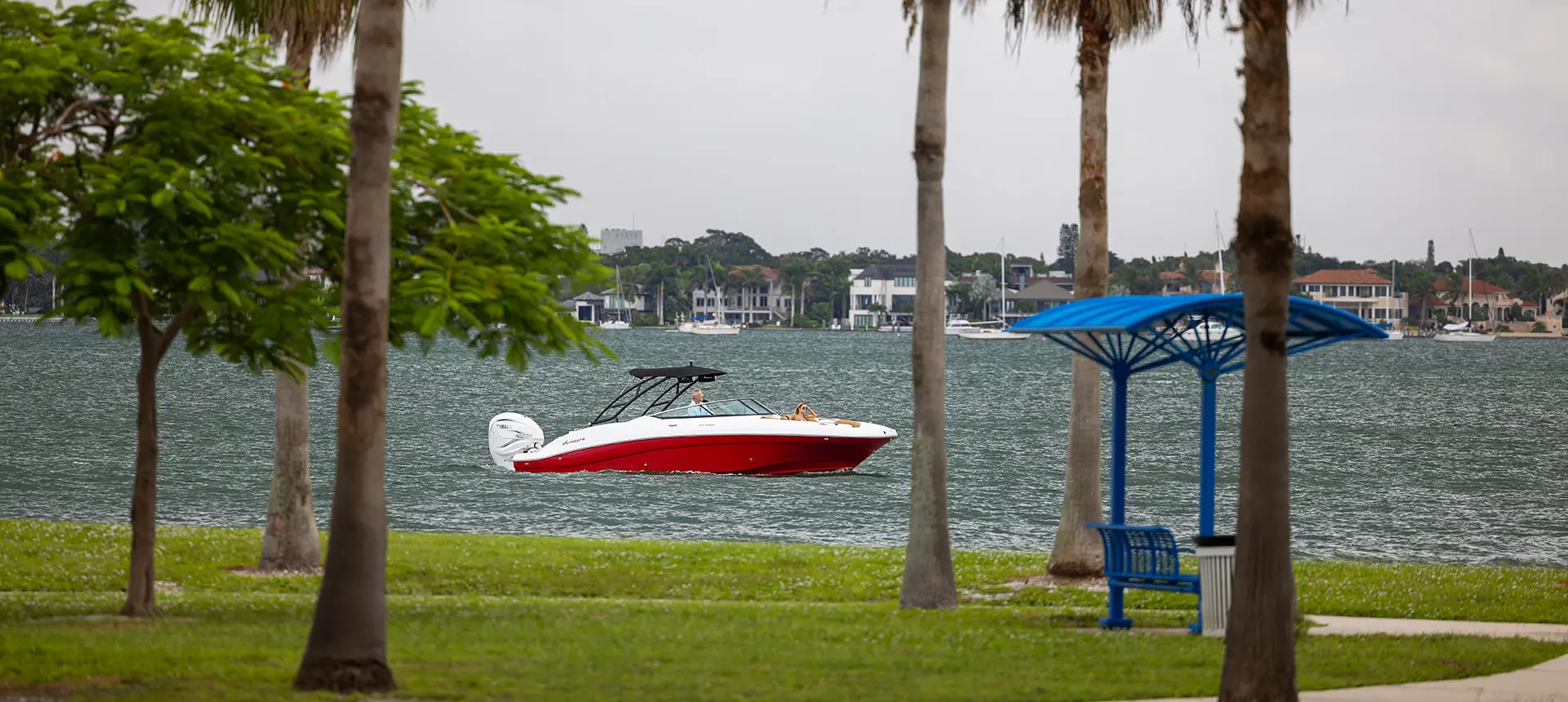 long distance shot through trees of a hurricane sundeck 2690 ob deck boat on the ocean