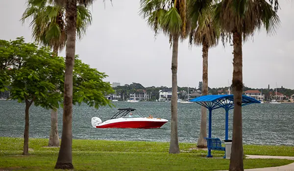 long distance shot through trees of a hurricane sundeck 2690 ob deck boat on the ocean