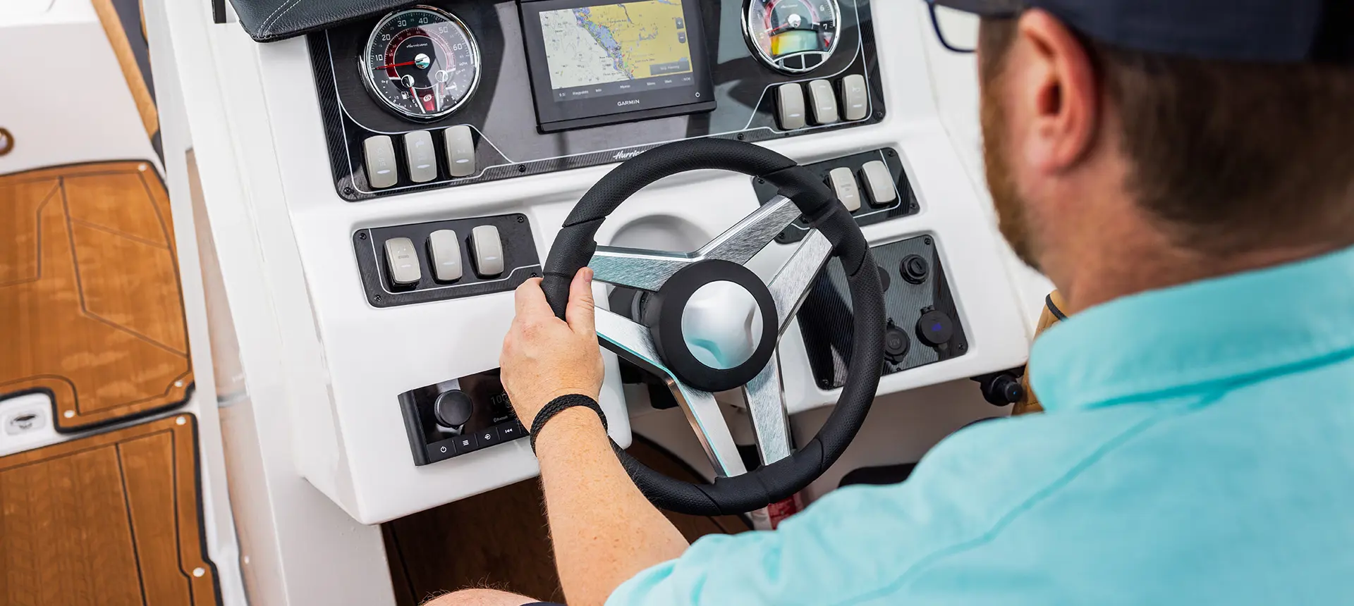 man at the helm with his hand on the wheel of a hurricane sundeck 2690 ob deck boat