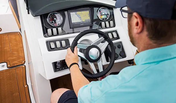 man at the helm with his hand on the wheel of a hurricane sundeck 2690 ob deck boat