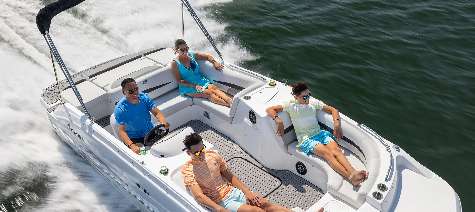 Aerial view of 4 people enjoying a lake cruise on a Hurricane SunDeck Sport I/O deck boat.