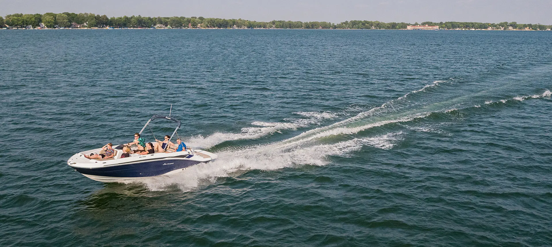 6 people cruising the lake on a Hurricane SunDeck Sport I/O deck boat.