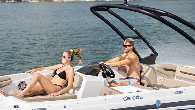Man and woman smiling while cruising on a Hurricane SunDeck Sport I/O deck boat.