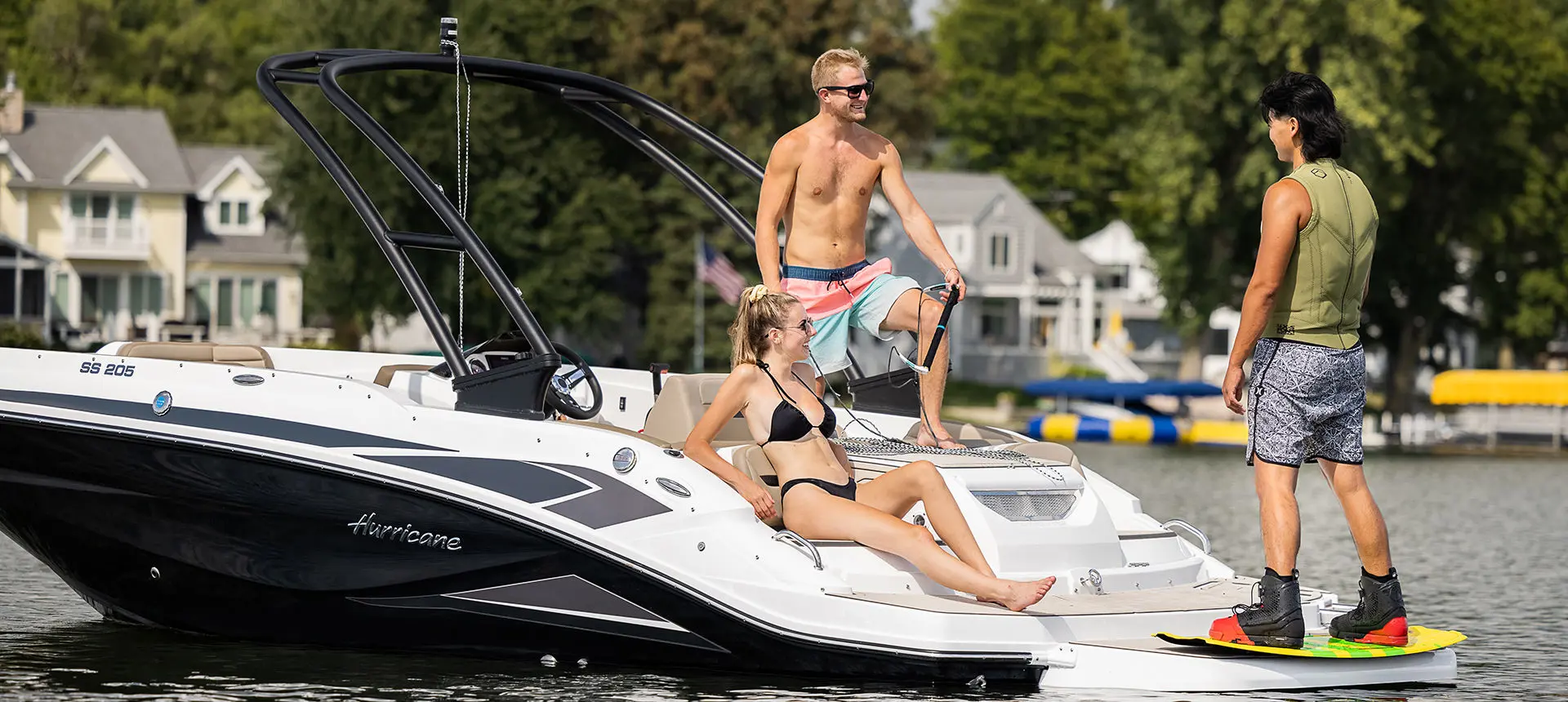 Man preparing to wake board behind a Hurricane SunDeck Sport I/O deck boat.