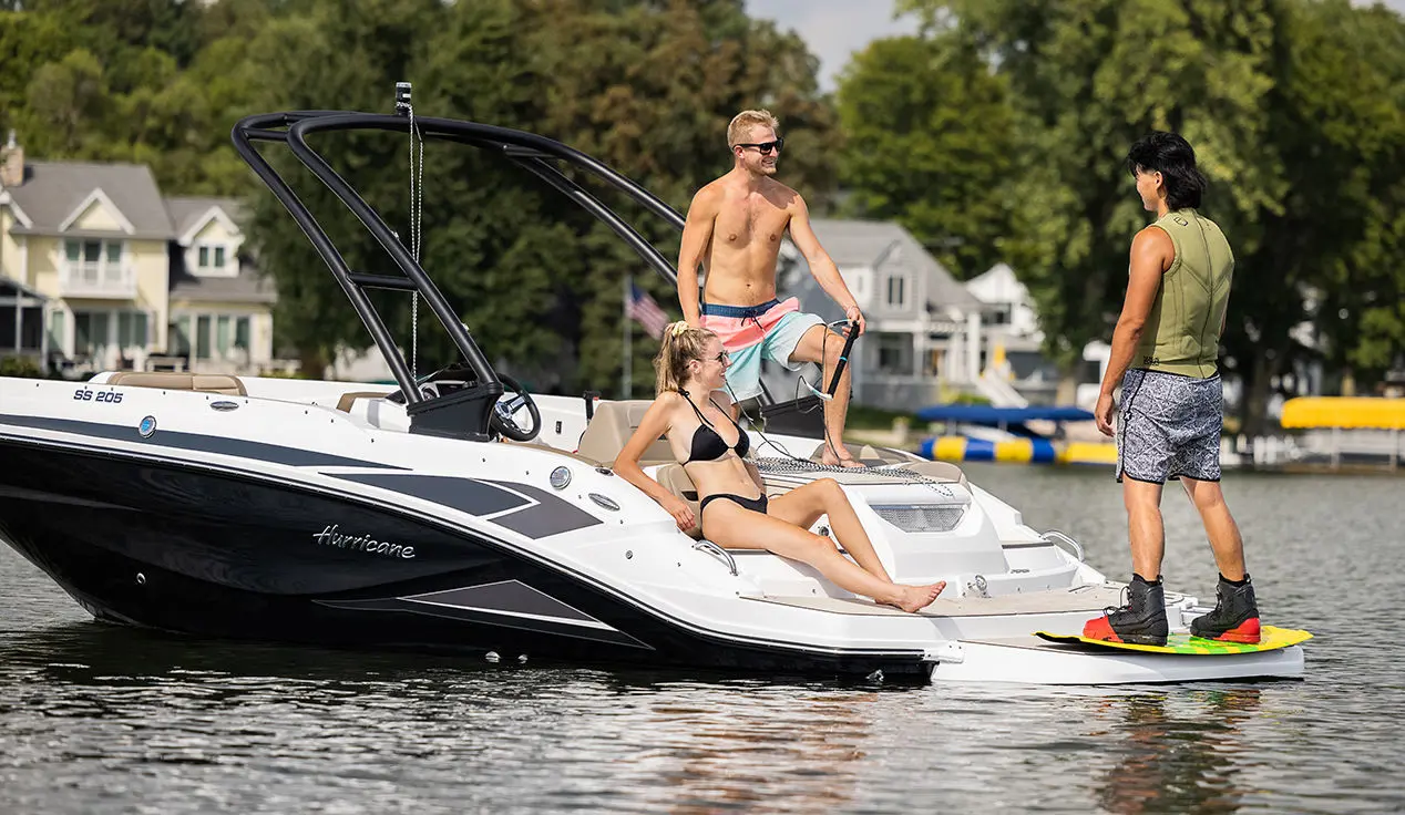 Man preparing to wake board behind a Hurricane SunDeck Sport I/O deck boat.