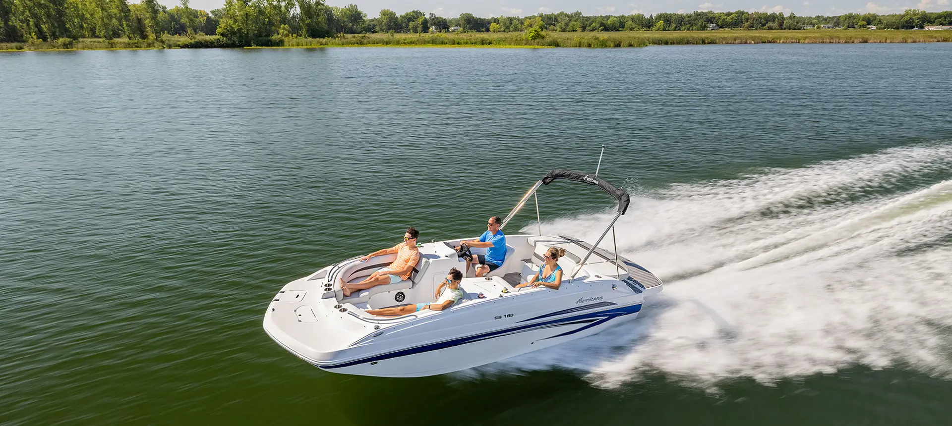 Hurricane SunDeck Sport 188 IO deck boat speeding across a lake.