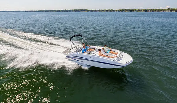 Side profile of a Hurricane SunDeck Sport 188 IO deck boat cruising on a lake.