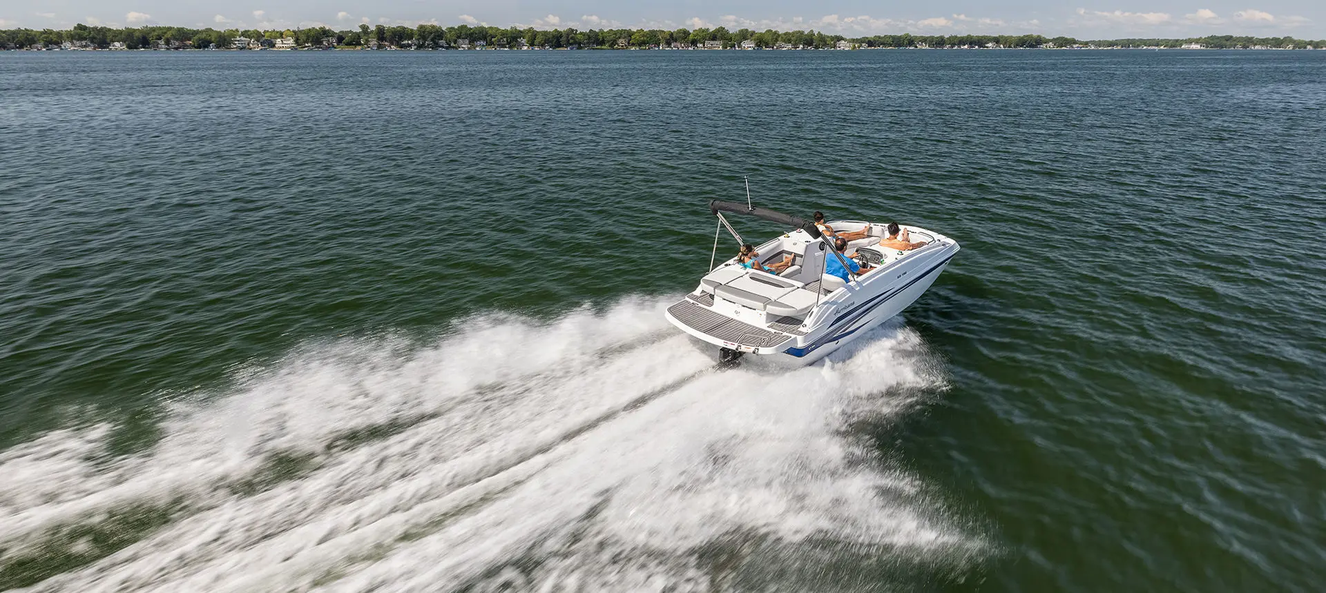 Stern focused view of a Hurricane SunDeck Sport 188 IO deck boat cruising on a lake.