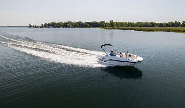 Side profile of a Hurricane SunDeck Sport 188 IO deck boat cruising on a lake.