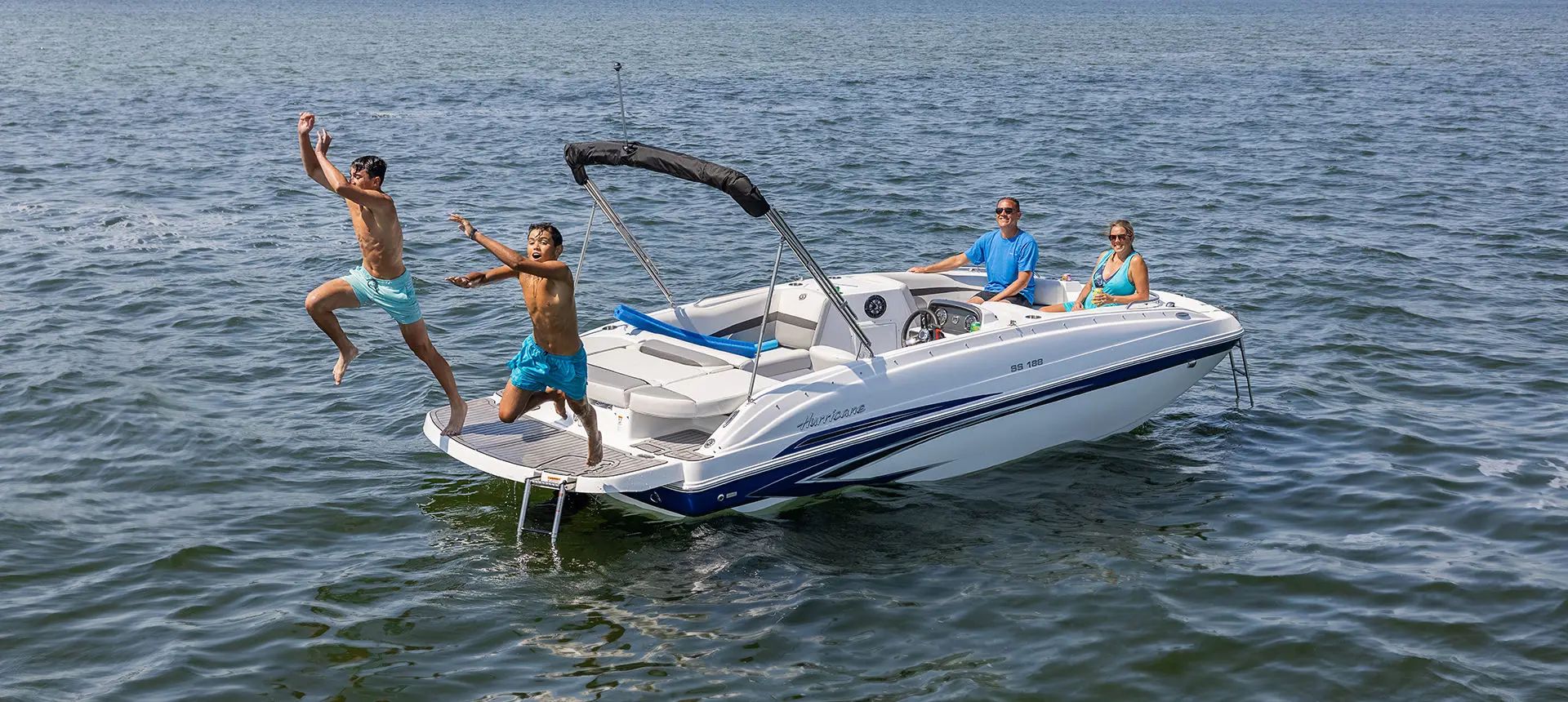 Kids jumping into the lake off the stern of a Hurricane SunDeck Sport 188 IO deck boat.