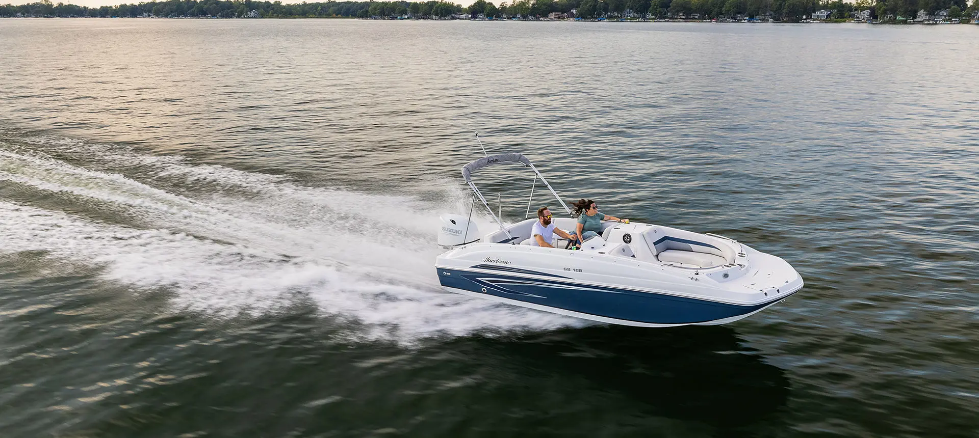 side view of a blue hurricane sundeck sport ob boat on a lake