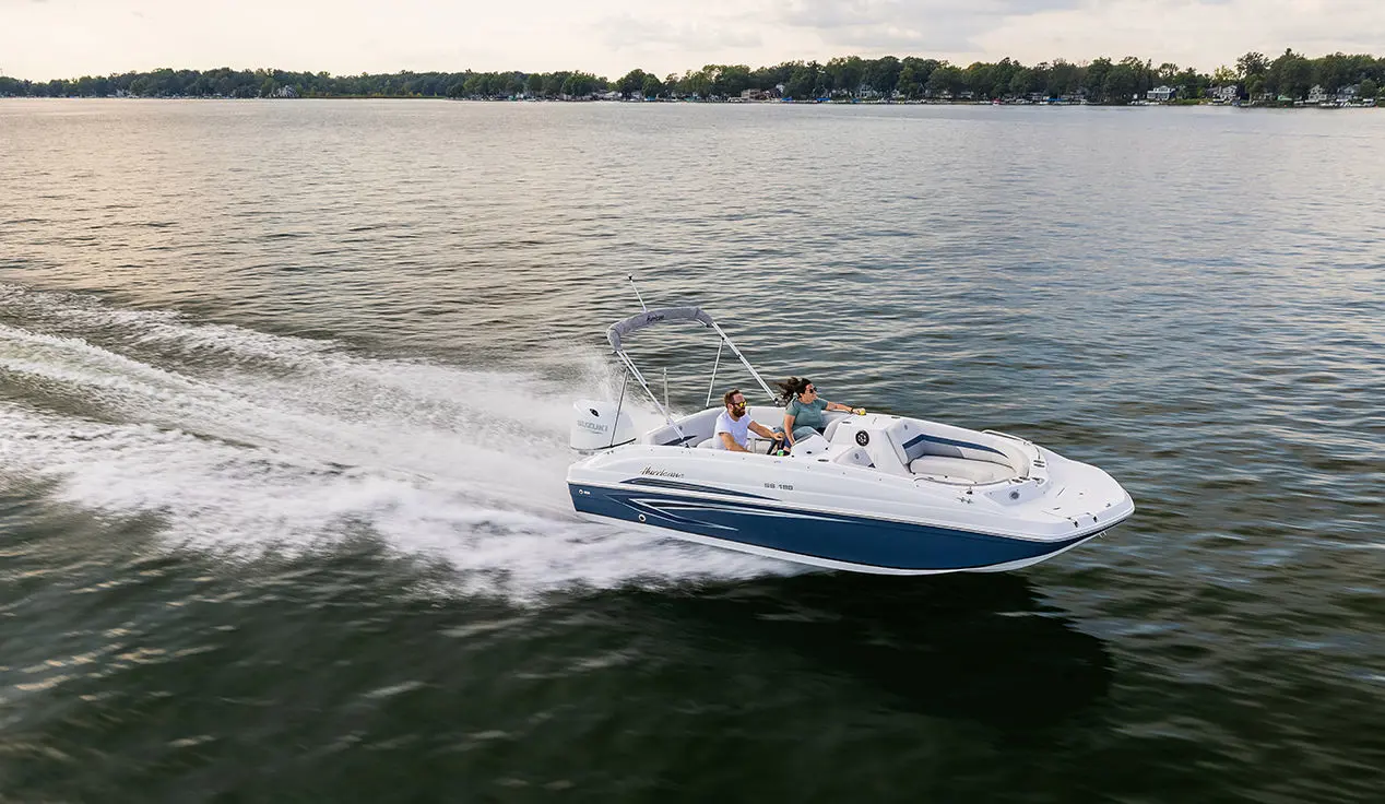 side view of a blue hurricane sundeck sport ob boat on a lake