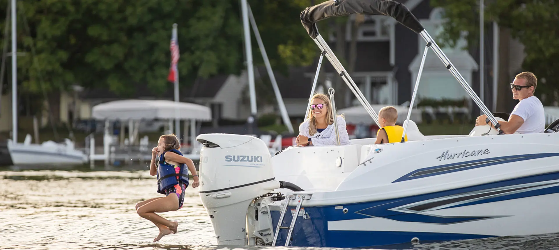 girl jumping into the water off the stern of a hurricane sundeck sport ob boat