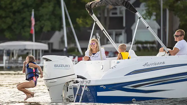 girl jumping into the water off the stern of a hurricane sundeck sport ob boat