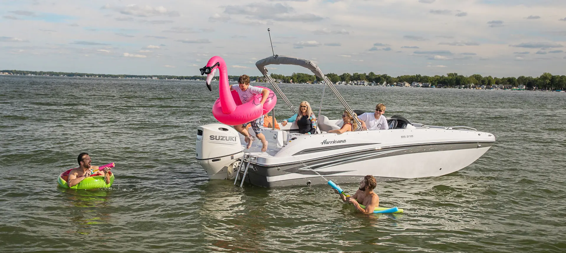 boy jumping into the water with a pink flamingo floatie off the stern of a hurricane sundeck sport ob boat