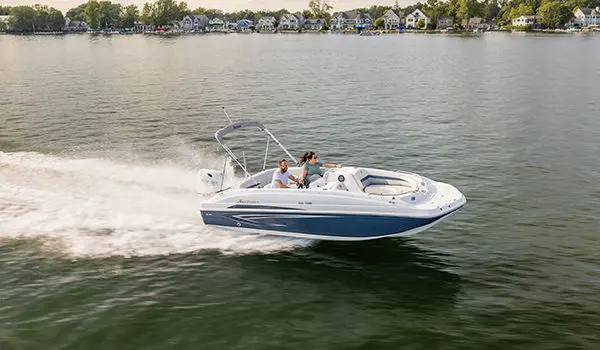 Couple speeds across a lake on a Hurricane SunDeck Sport 188 OB deck boat.