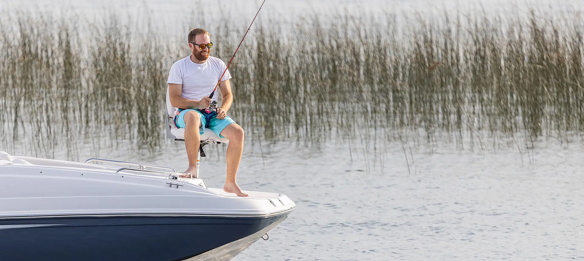 Man fishing off the bow of a Hurricane SunDeck Sport 188 OB deck boat.