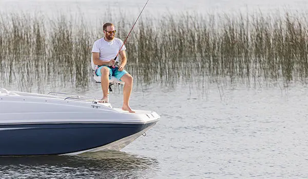 Man fishing off the bow of a Hurricane SunDeck Sport 188 OB deck boat.