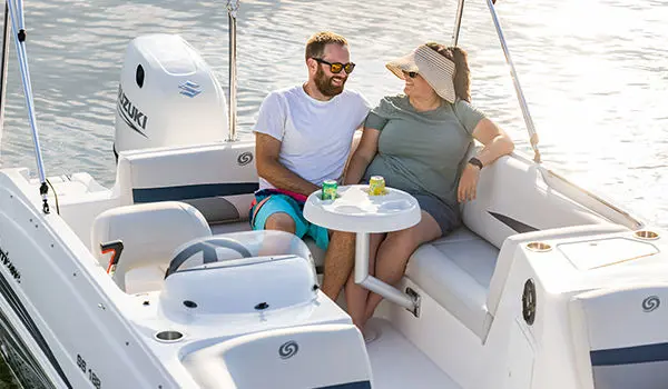 Couple relaxing at the stern table on a Hurricane SunDeck Sport 188 OB deck boat.