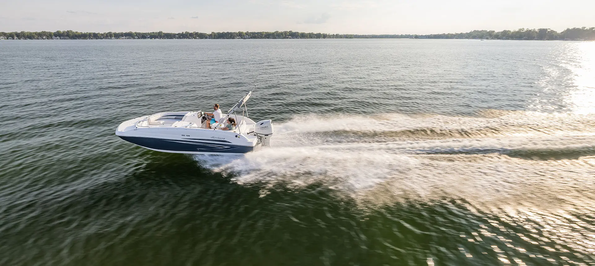 Hurricane SunDeck Sport 188 OB deck boat cruising on a lake.