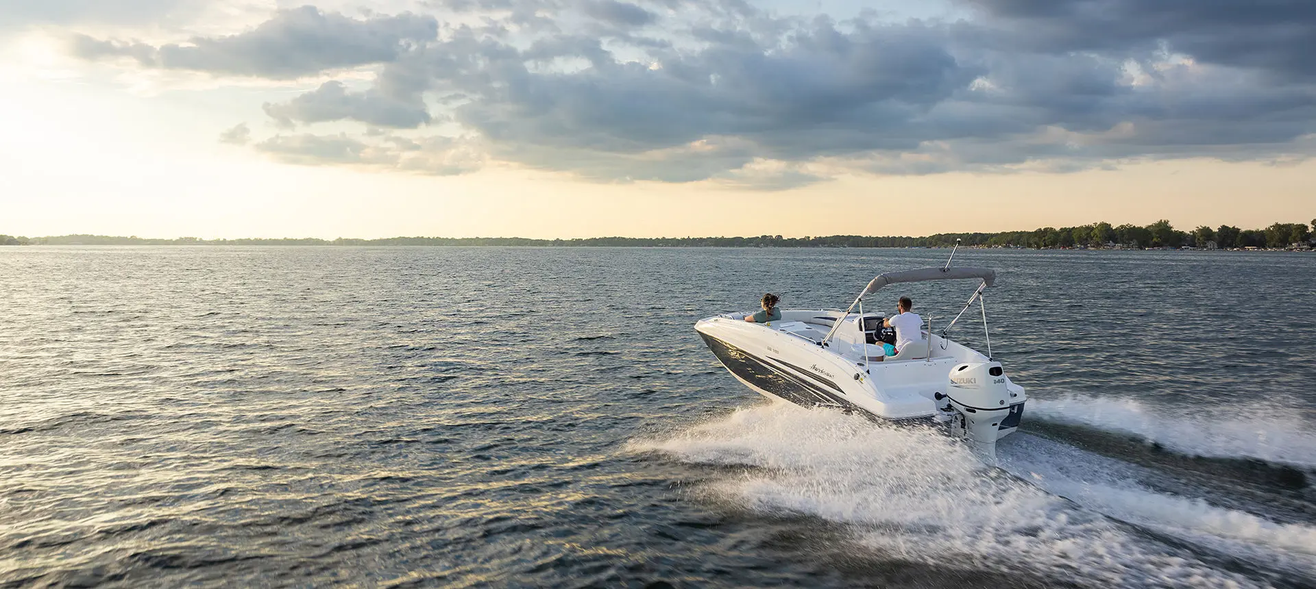 Stern focused view of a Hurricane SunDeck Sport 188 OB deck boat on a lake.