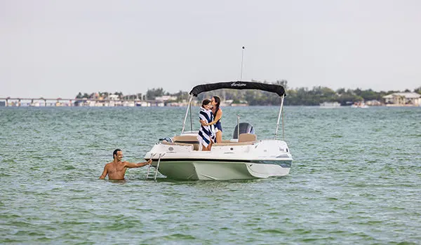 mom kissing daughter while dad starts to climb the bow ladder on a hurricane sport 201 ob deck boat