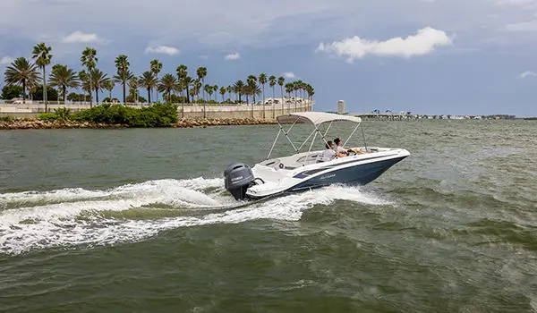 Hurricane SunDeck Sport 205 OB deck boat cruising by the coastline.