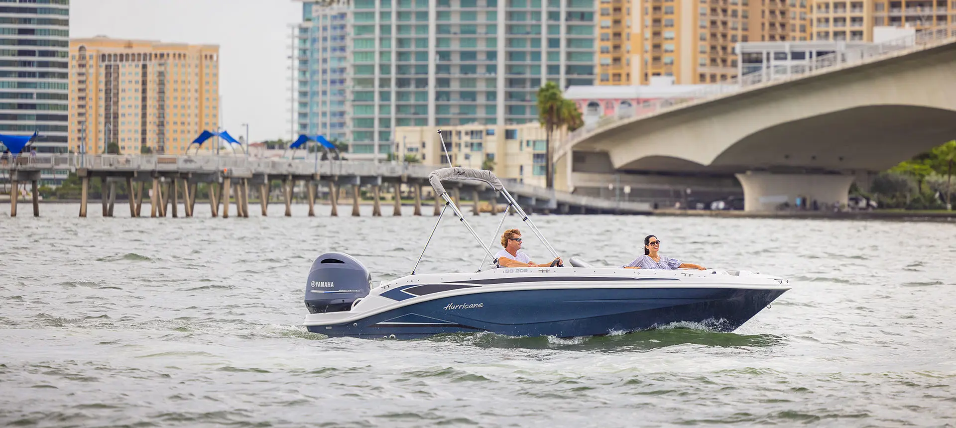Side view of a Hurricane SunDeck Sport 205 OB deck boat floating on the ocean.