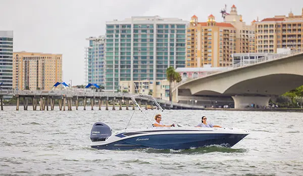 Side view of a Hurricane SunDeck Sport 205 OB deck boat floating on the ocean.