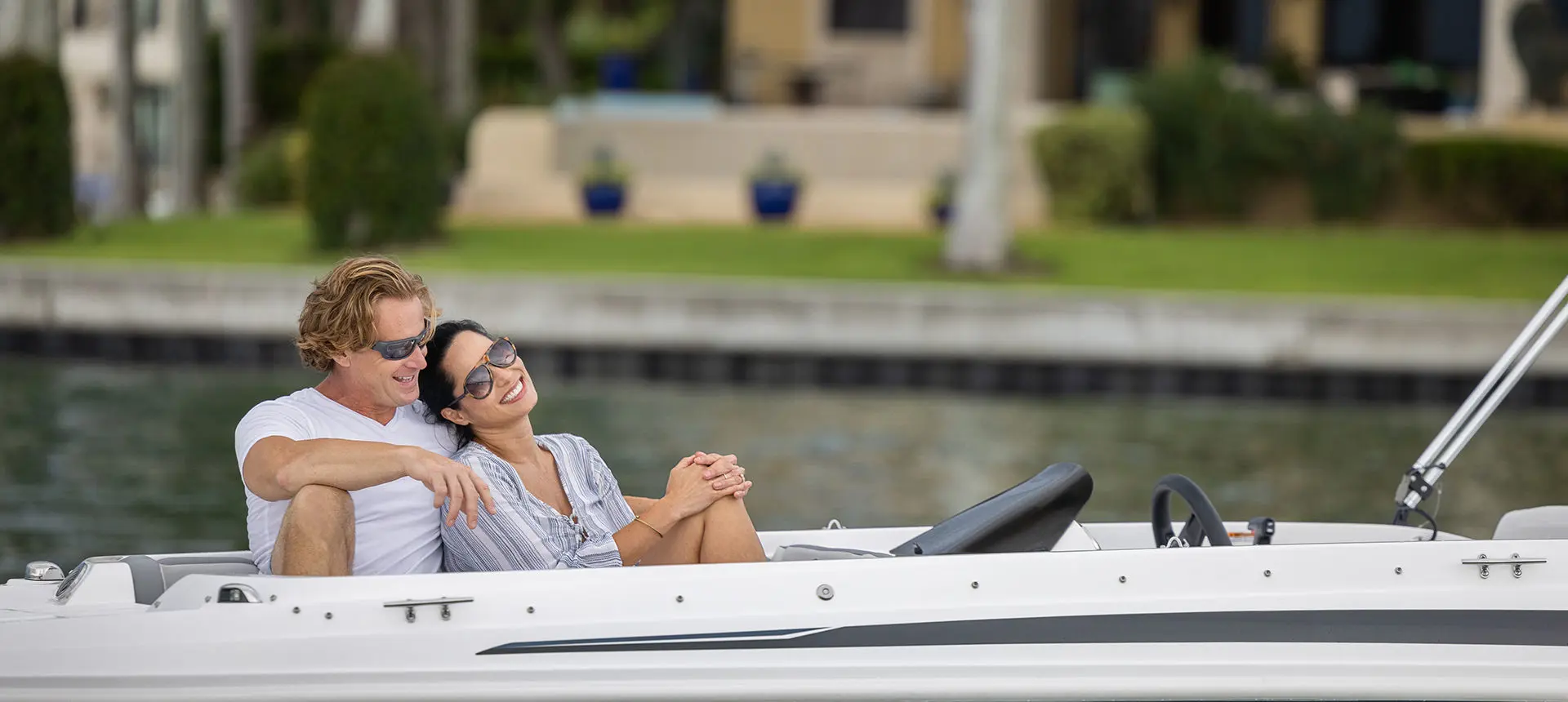 A couple cuddling on the bow seats of a Hurricane SunDeck Sport 205 OB deck boat.